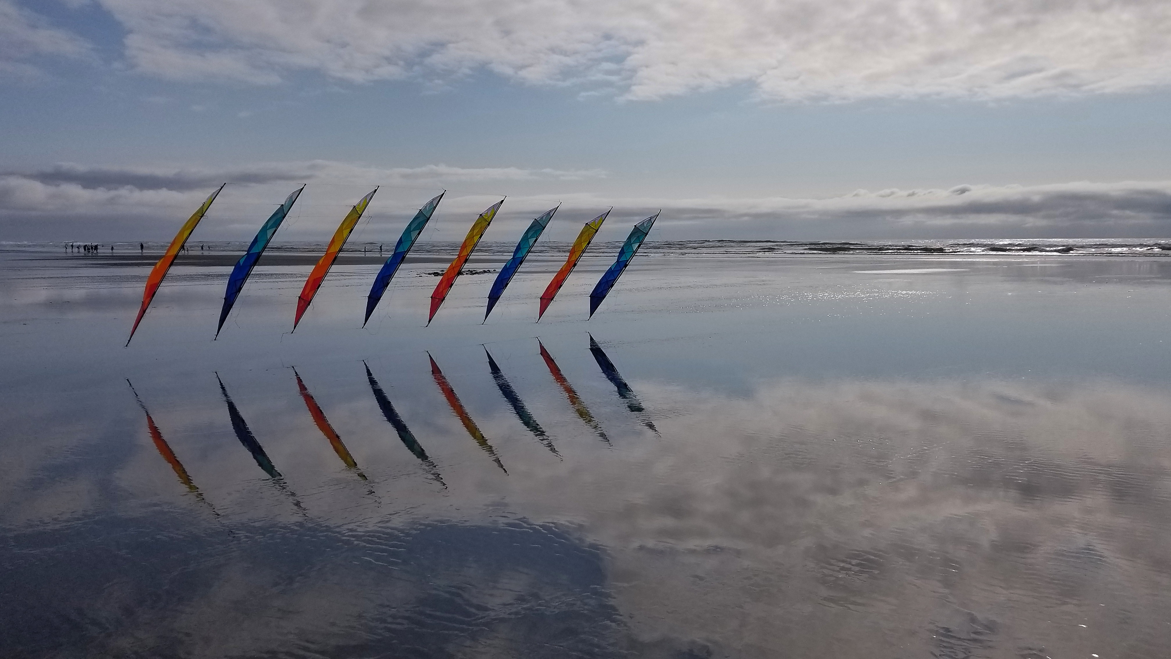 Mosaic sport kites flying low above still water